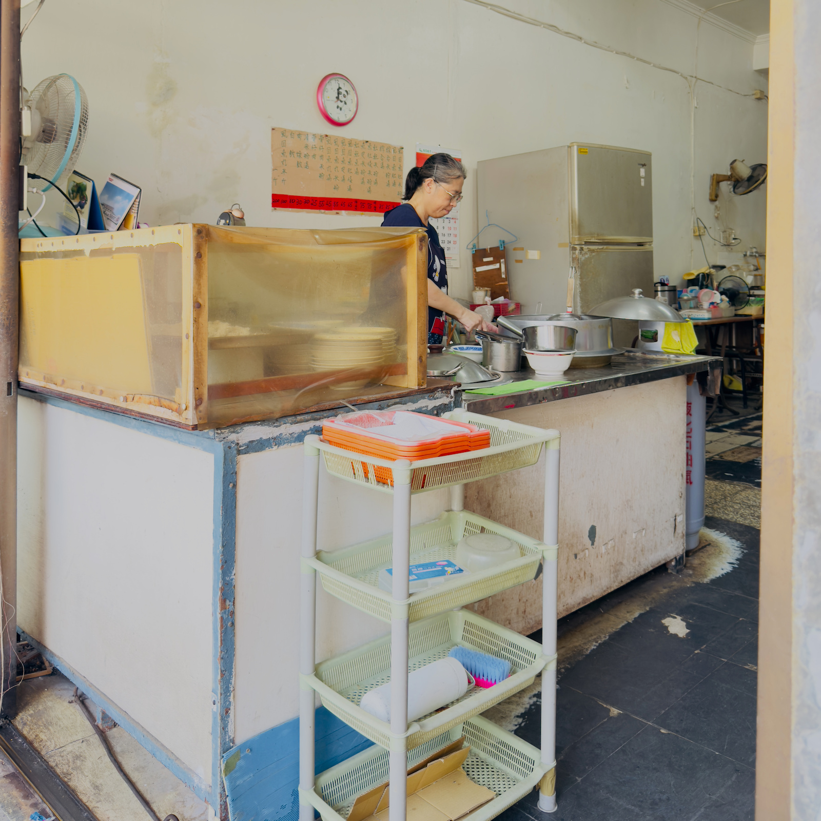 三山國王廟虱目魚米粉店純樸的廚房內部，老闆娘正在備料，呈現老店每日現做的堅持。