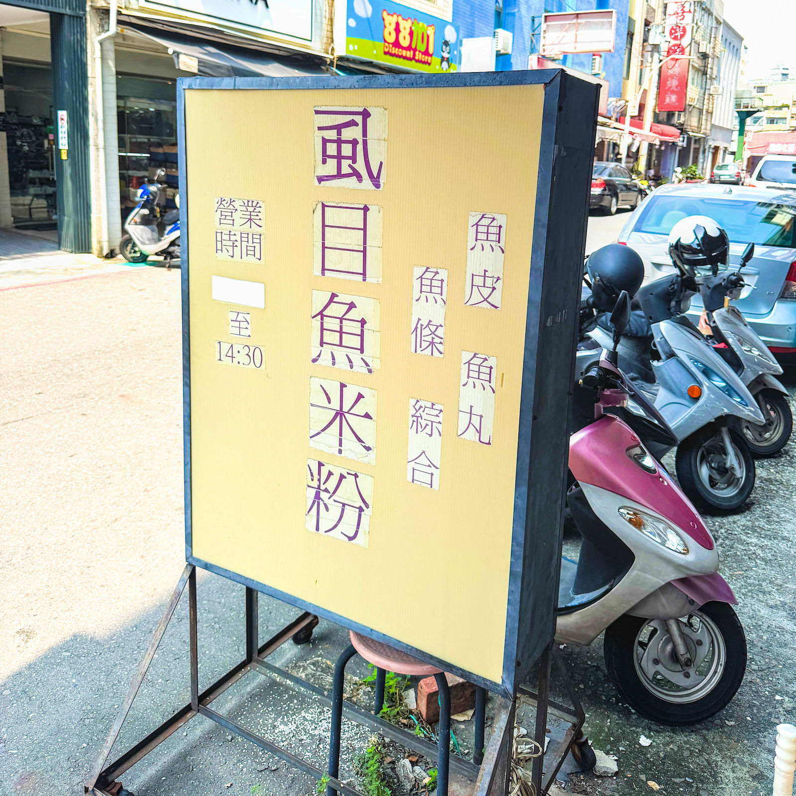 三山國王廟虱目魚米粉店門口的黃色立牌，寫有虱目魚米粉和營業時間，作為鹽埕區隱藏美食地標。