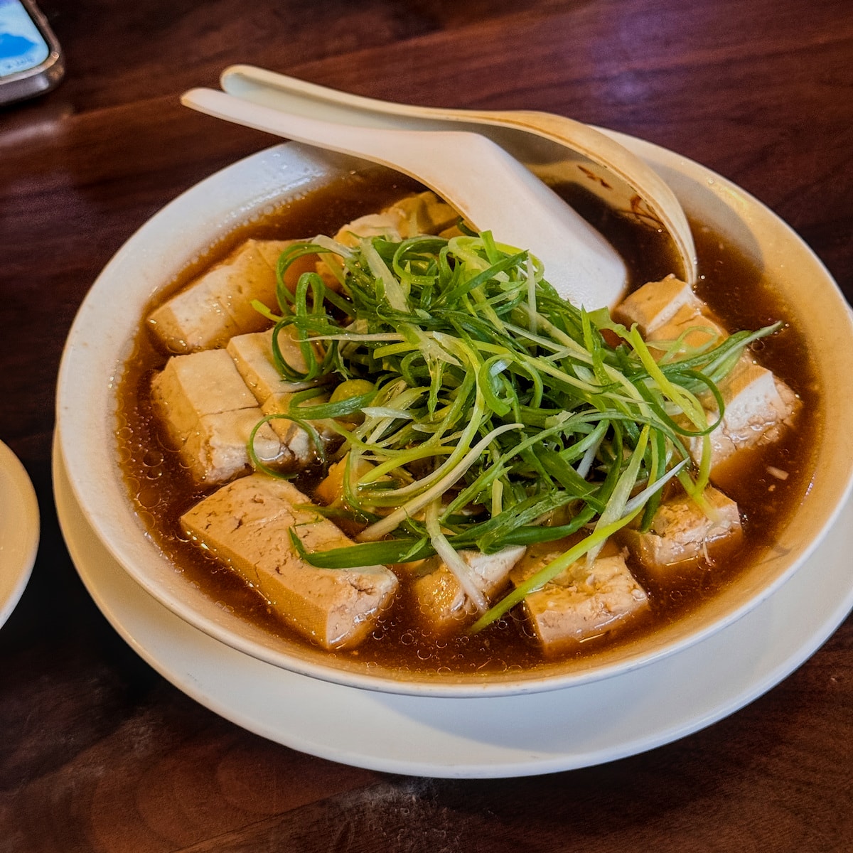 福記清蒸臭豆腐:極致的重口味享受 鋪滿肉燥與鮮綠蔥絲的清蒸臭豆腐,湯頭鮮甜誘人