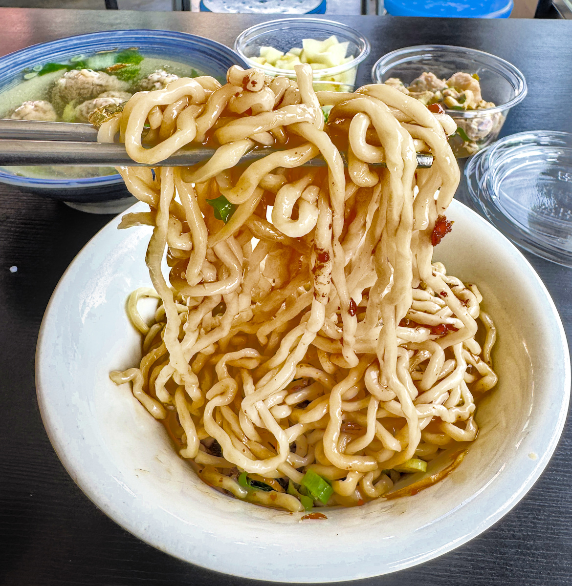 以筷子夾起念姨麵館Ｑ彈有勁的拉麵麵條，展現濃郁醬汁層次感