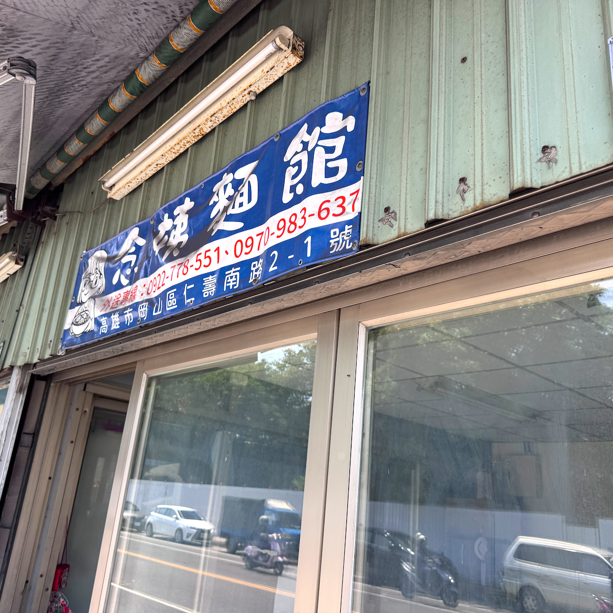 念姨麵館位於岡山區仁壽南路的藍色招牌外觀，顯示外送專線與服務地址