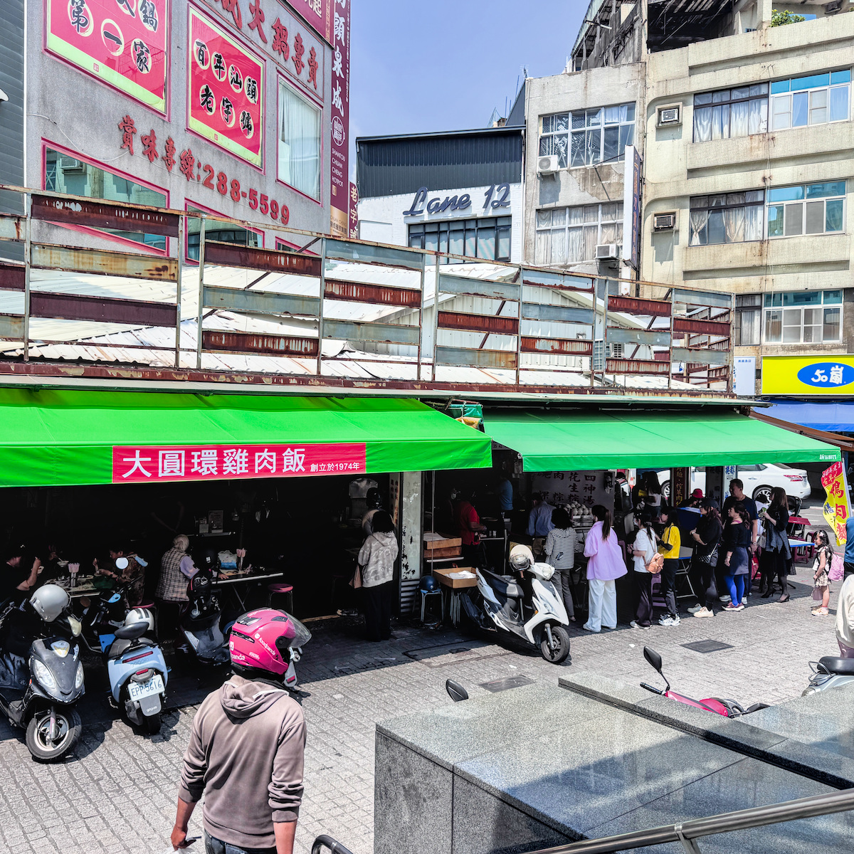 大圓環鴨肉麵店外用餐環境，紅色圓凳坐滿來自日本與泰國的觀光客與在地人併桌