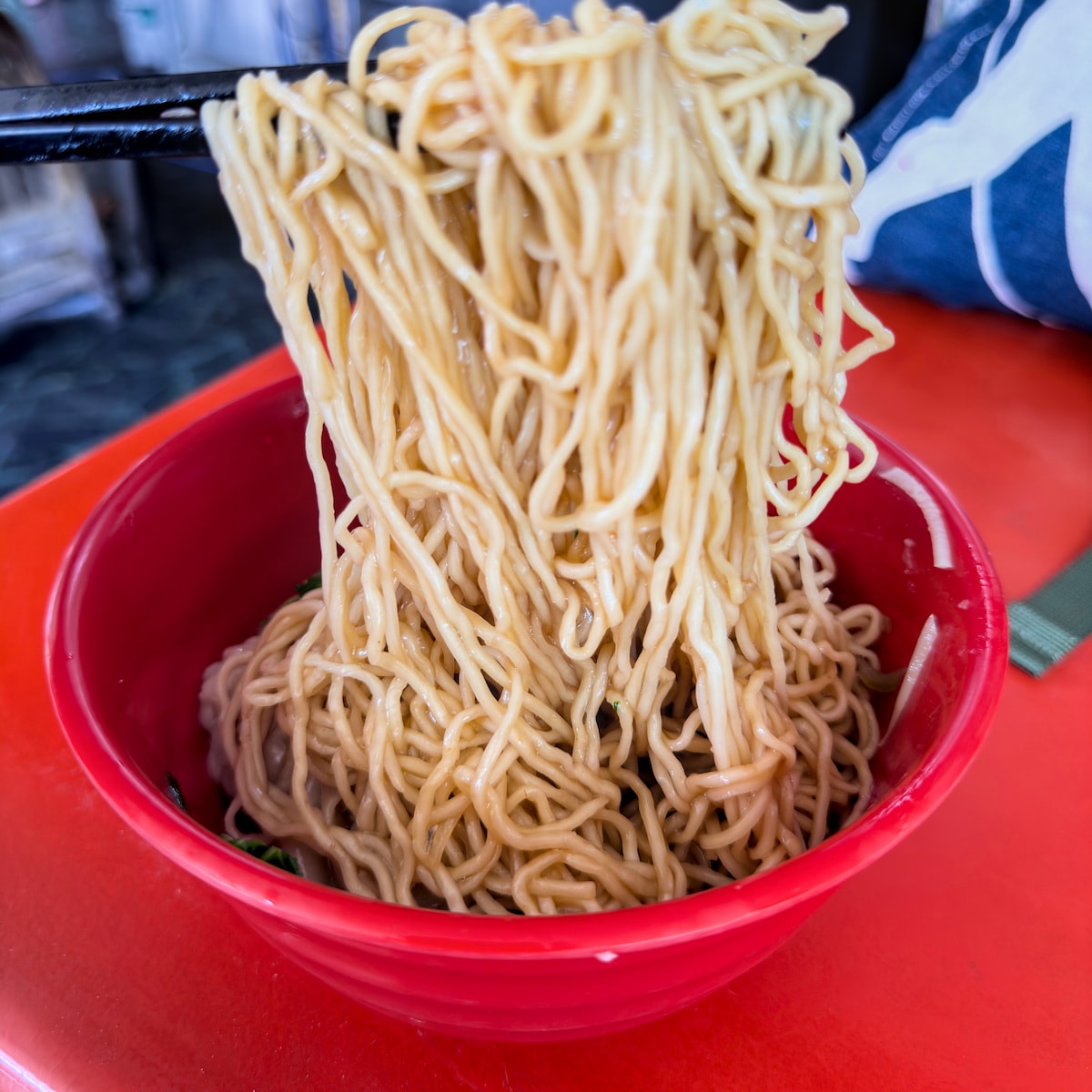 廣招英溫州餛飩乾麵的細麵麵條拉起特寫，吸附油蔥香氣令人食指大動