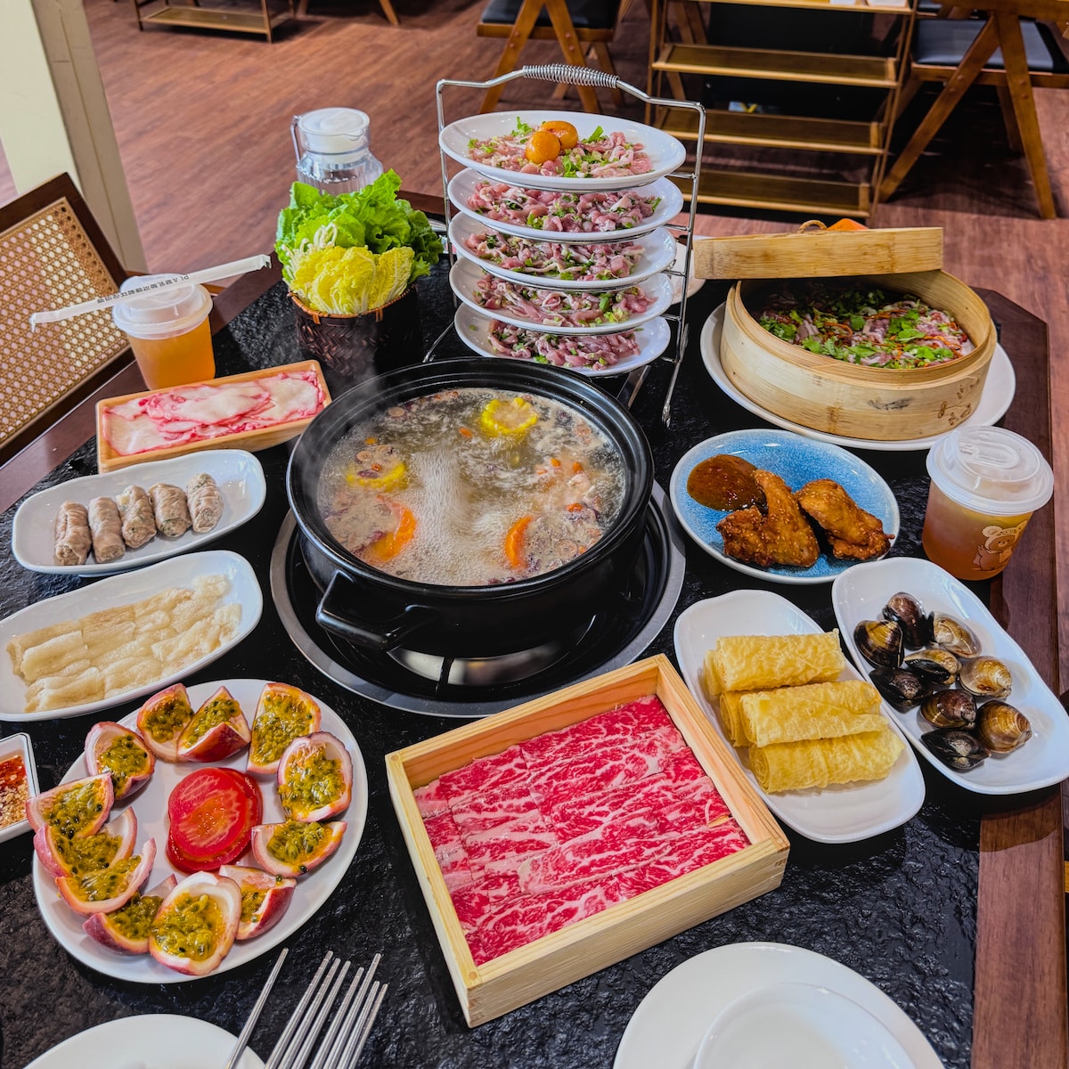 烽味廣味雞煲火鍋精選特色料理全家福 烽味廣味雞煲火鍋包含百香果鍋底、雪花牛與多層架雞肉的澎湃桌面全景