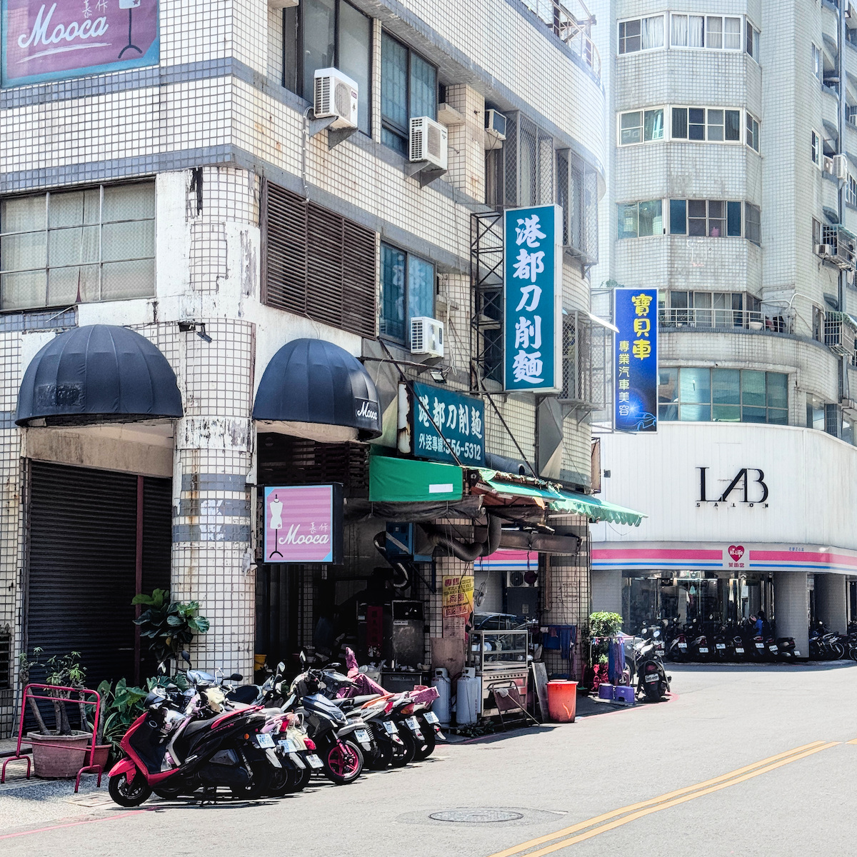 位於高雄左營區正心街的港都刀削麵店面外觀，充滿台式庶民生活感的老店招牌與排隊等候的機車人潮