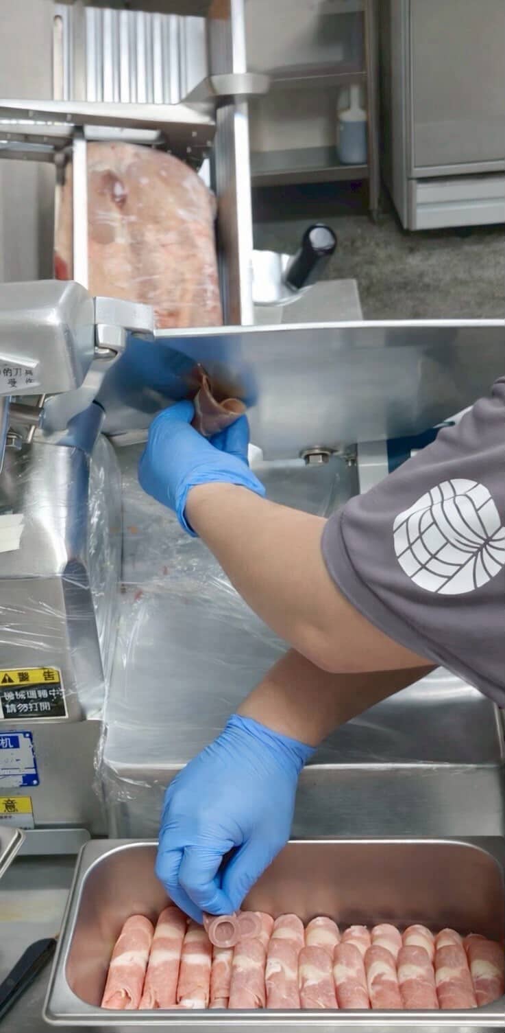 青木堂鍋物職人現切原肉作業區，工作人員戴手套確保衛生