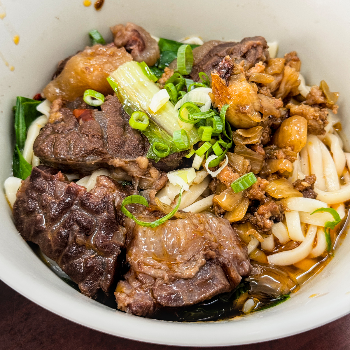 老楊牛肉麵的招牌牛肉拌麵小碗，配有豐富牛肉塊、肉燥與蔥花