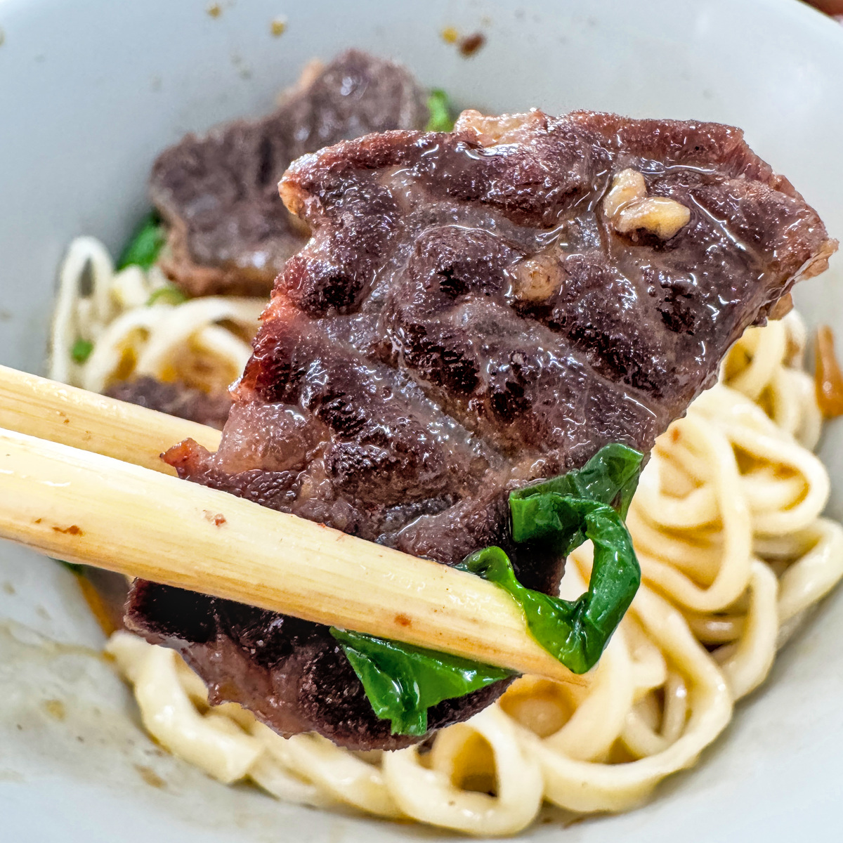 夾起老楊牛肉麵軟嫩多汁牛肉塊與彈牙拉麵的美味瞬間